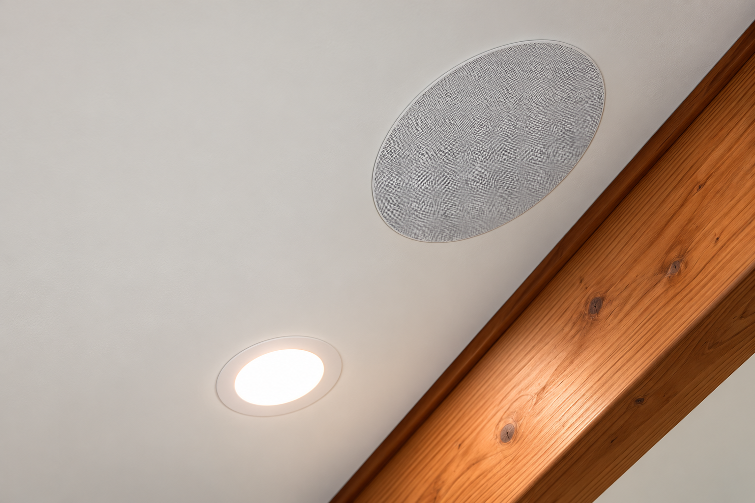 Detail of a flush ceiling speaker and recessed light beside a timber beam in the HES Standley Redmond installation